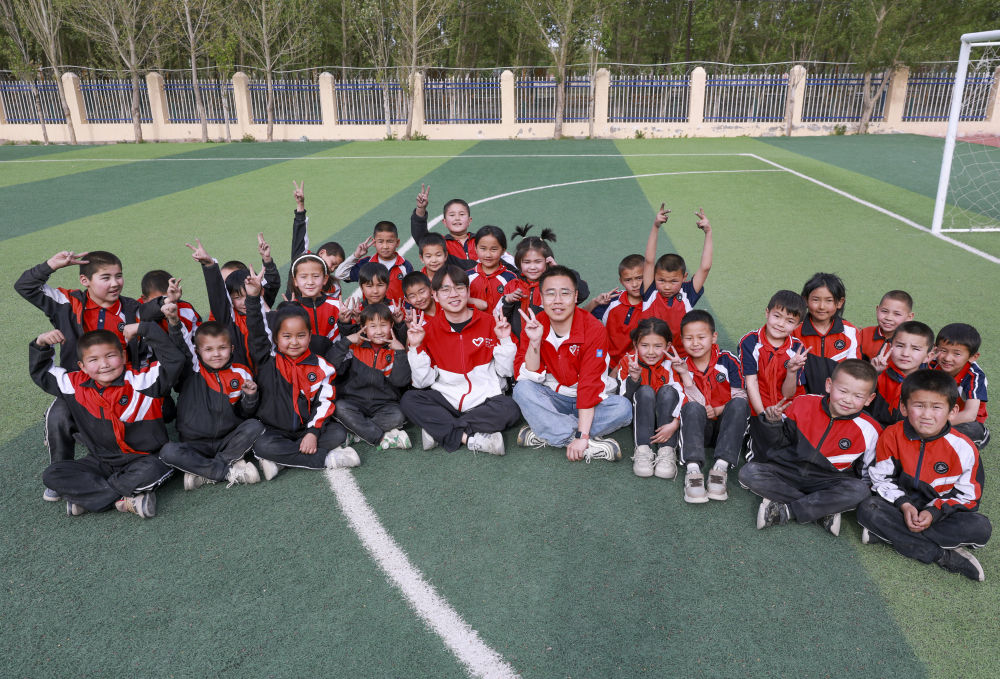 4月23日，在新疆克州阿圖什市哈拉峻鄉(xiāng)謝依特小學，支教教師王俊文（中左）、李軻凡（中右）和學生在一起。